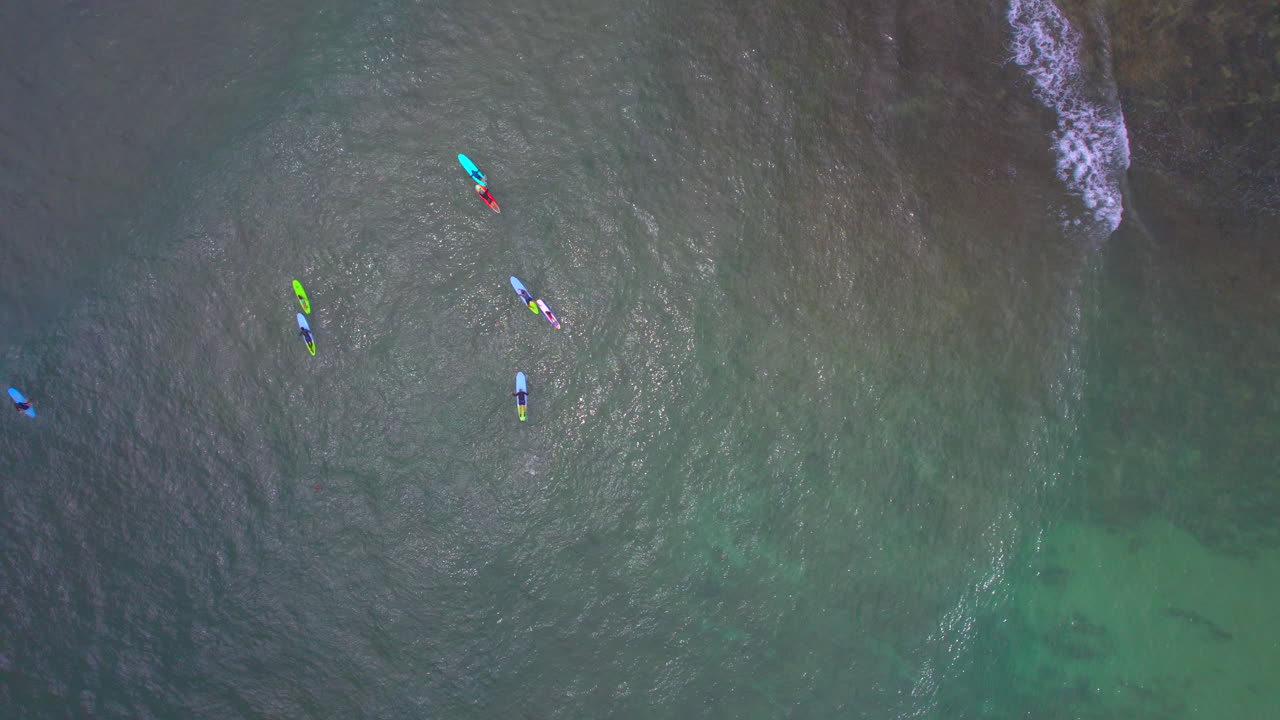 Raising up aerial view of surfers learning to surf off the coast of Hale'iwa Oahu Hawaii North Shore