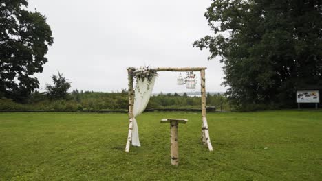 hacer zoom en el arco de boda de madera de abedul minimalista en el parque en un día nublado