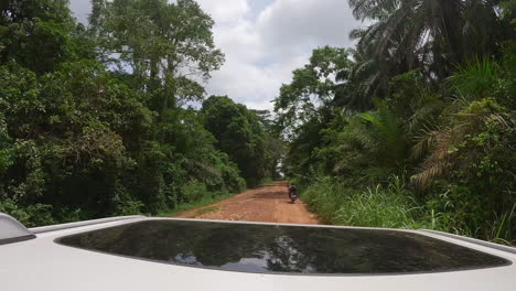 hyperlapse footage on top of a car that is going through villages and the jungle on a dirt road