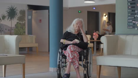 slow motion shot of an elderly woman in a wheelchair sitting in a retirement home