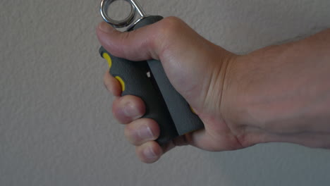 man working on his grip and forearm strength with a handgrip strengthener