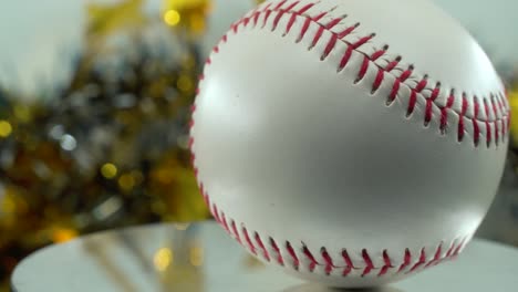 cinematic slow close-up shot of a white base ball, red stitches baseball on a shiny stand, christmas blurry decorations in the background, professional studio lighting, 4k video pan right