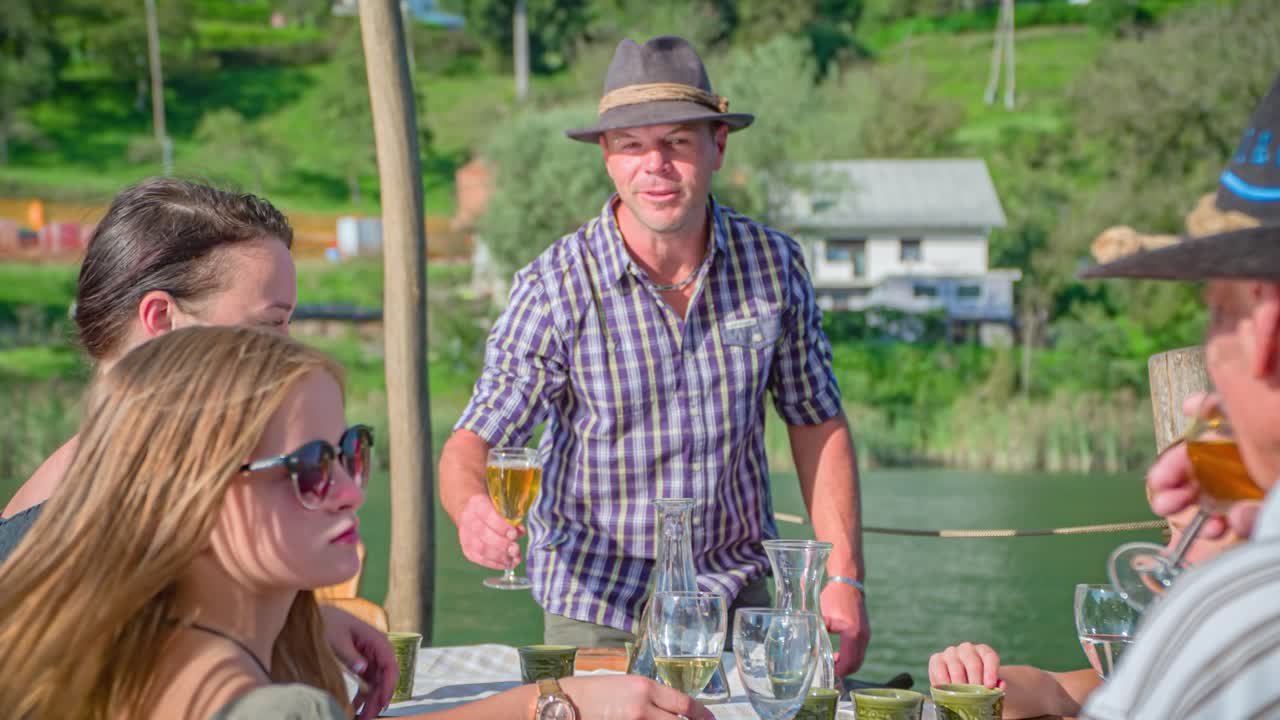 Young Caucasian man salutes wine glass with family on small boat down the river