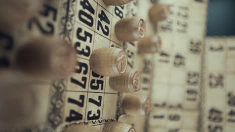 A-Vertical-Macro-video-of-a-Bingo-board,-studio-lights,-120-fps,-slow-motion,-wooden-chip-digits,-Raw-footage,-vintage-lottery-desk-game,-card-numbers,-crane-pull-back-movement