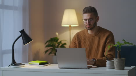 Mann-Merkt-Sich-Das-Passwort-Einer-Site-Oder-Eines-Profils-Im-Internet-Und-überprüft-Es-Per-Notebook,-Während-Er-Abends-Zu-Hause-Arbeitet.-Männerporträt-Im-Wohnzimmer