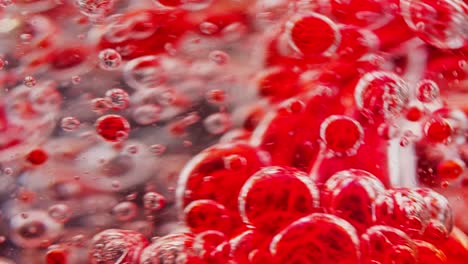 macro shot of red bubbles getting mixed in water, moving around