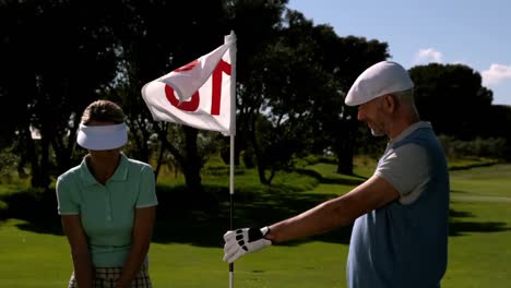 Golfista-Sonriente-Sosteniendo-La-Bandera-Del-Hoyo-18-Para-Su-Compañero