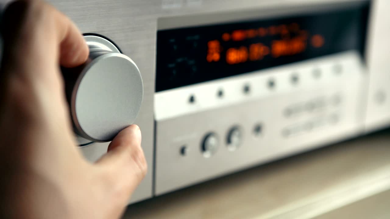 4k 남자의 손이 음악 증폭기에 소리를 켜고 있습니다.