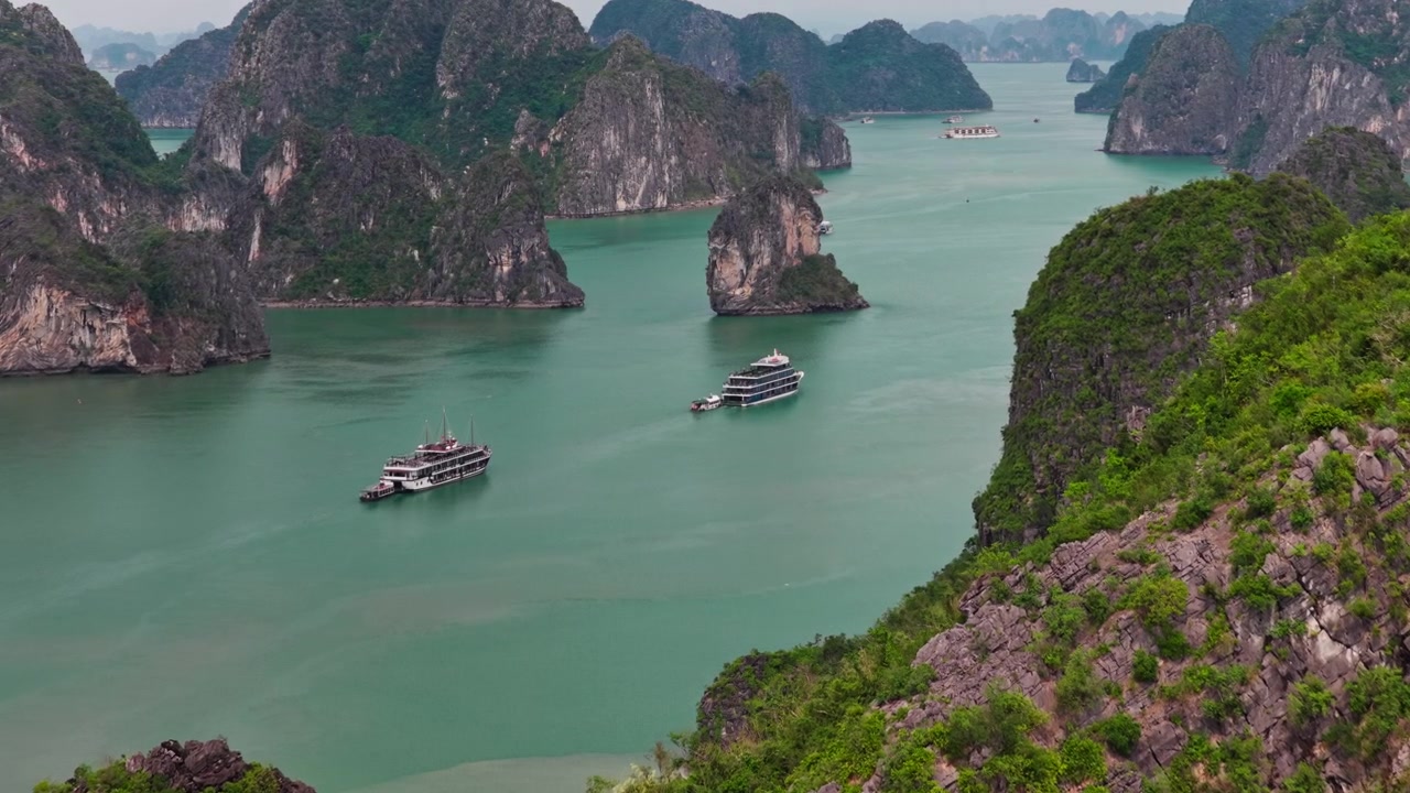 Ha Long Bay breed luchtbeeld met dolly-in, met kalkstenen karsten en cruiseschepen die varen in smaragdgroen water in Vietnam.