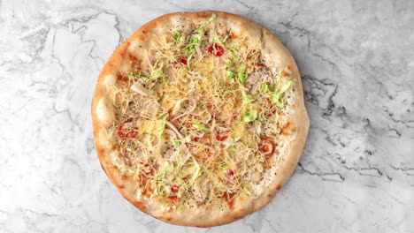 pizza fresca redonda con verduras, ensalada y pollo gira en una mesa de mármol, vista de arriba, espacio de copia. animación de bucle sin costuras