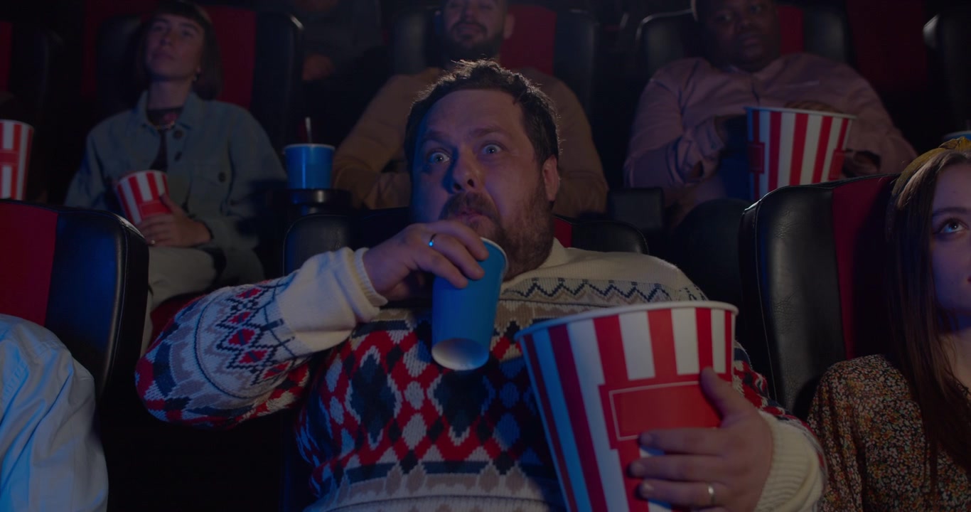 Homem dormindo no cinema enquanto segura pipoca