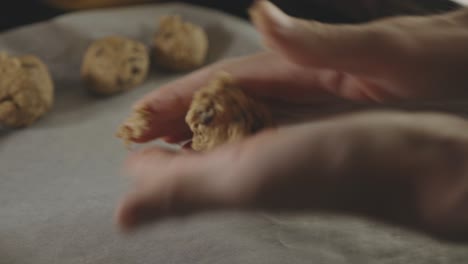 baker's hands rolling chocolate chip cookie for baking in the kitchen - close up