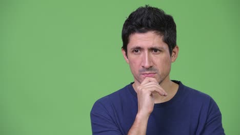 serious hispanic man thinking against green background