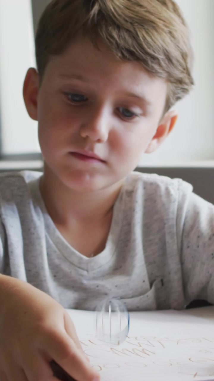 Video verticale: Bambino che disegna alla scrivania, un punto che si trasforma in un globo che oscura il viso per l'apprendimento
