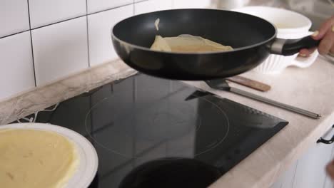 mujer da vuelta a los panqueques en una sartén y sonríe