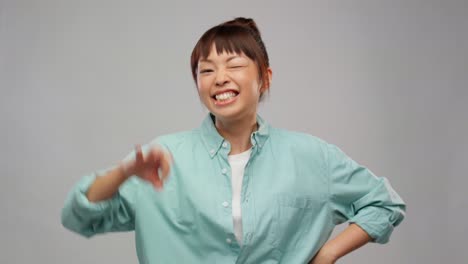 Happy-Asian-Woman-Dancing-Over-Grey.happiness-and-people-concept-happy-smiling-asian-woman-dancing-over-grey-background