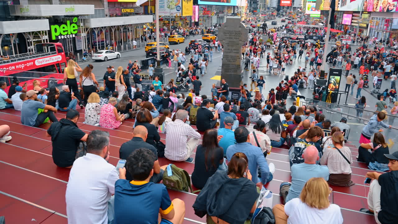 Pessoas durante o dia na Times Square. Visitantes relaxam nos degraus enquanto aproveitam a agitação da Times Square em Manhattan em uma tarde ensolarada