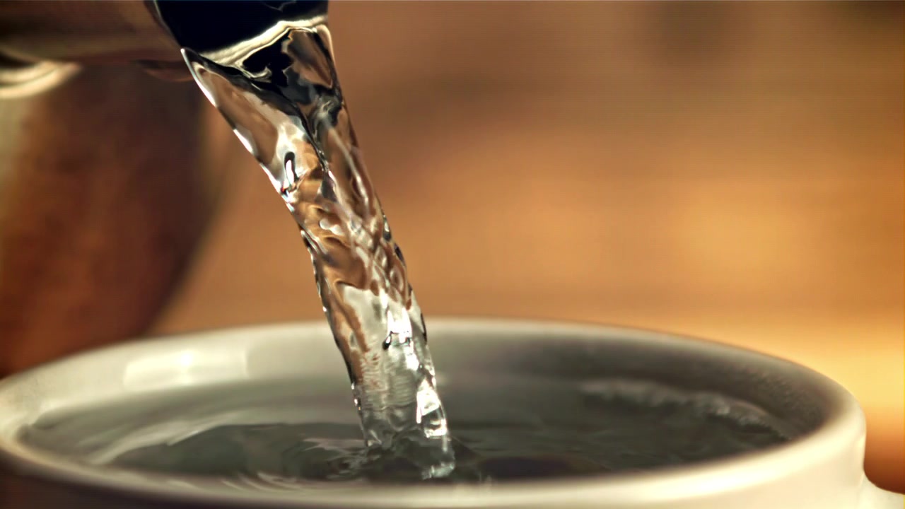 Primo piano di acqua calda versata in una tazza bianca