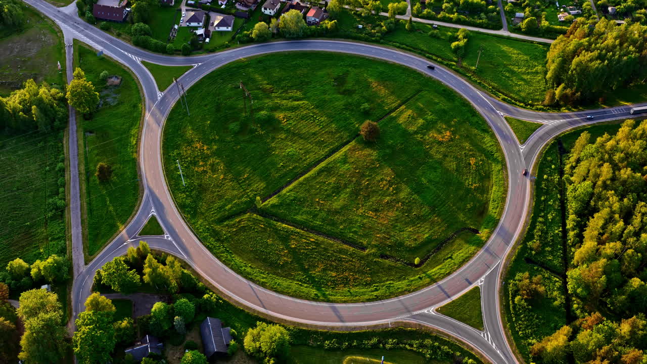 Drone hyperlapse of large traffic roundabout with vehicles and long shadows at sunset