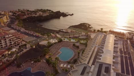 Puesta-De-Sol-Escénica-En-La-Isla-De-Tenerife-España-Drone-Revela-Un-Impresionante-Hotel-Resort-Ubicado-En-La-Costa-Del-Océano-Durante-Las-Horas-Doradas