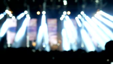 crowd at concert  and blurred stage lights of people dancing at the rock 'n roll concert.