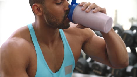 bodybuilder drinking a protein shake at a gym