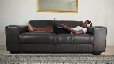 african lady laying on couch working from home on laptop