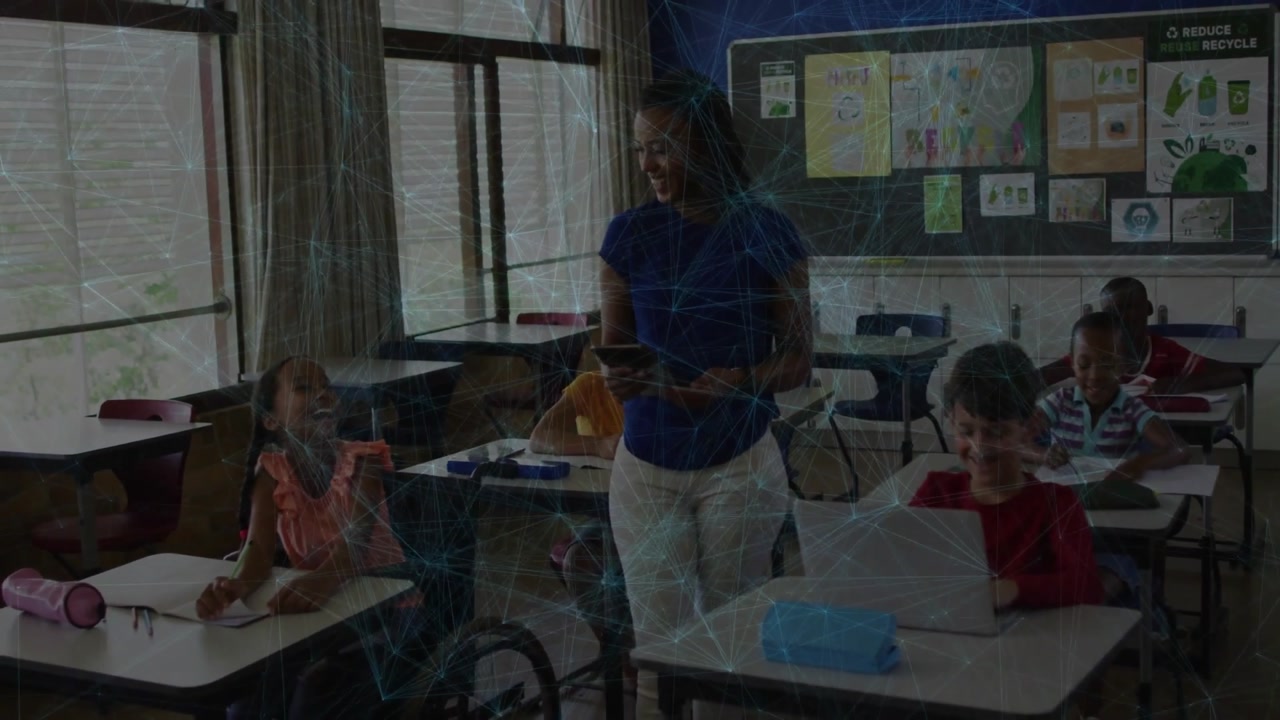 Teacher scrolling tablet glancing student work in classroom tapping laptop for engaging learning
