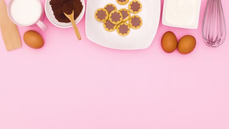 cookies in plate and ingredients for baking appear on top of pink theme. stop motion