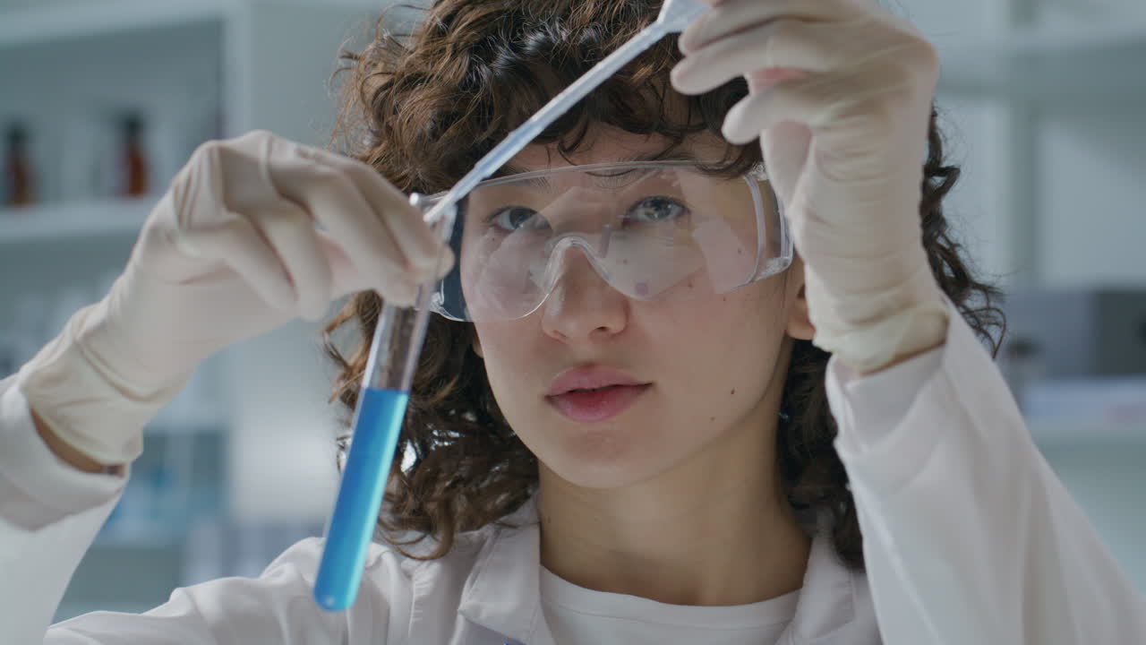 Female Lab Scientist Pouring Blue Liquid into Test Tube with Pipette