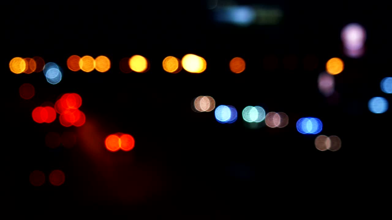 los círculos de bokeh en movimiento de las luces de los coches que corren por las calles de la ciudad. el fondo borroso de la ciudad, el tráfico nocturno.