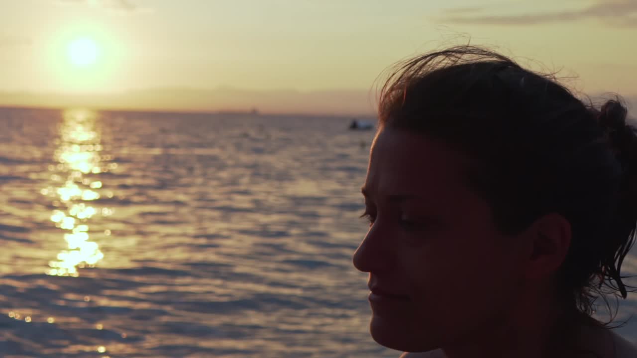 Close up on caucasian greek woman's face, with beautiful sunset at sea of Kalamata, Peloponnese , Greece