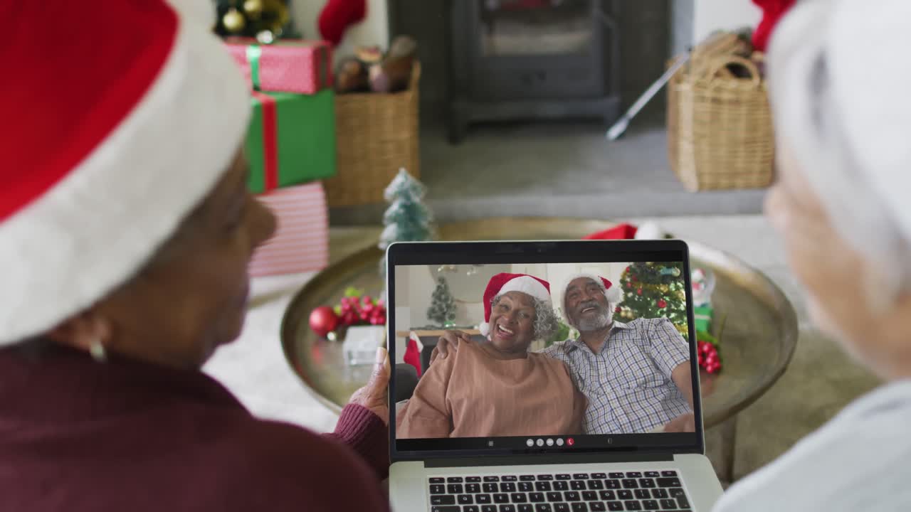 sonriendo diversas amigas mayores usando una computadora portátil para una videollamada de navidad con una pareja en la pantalla