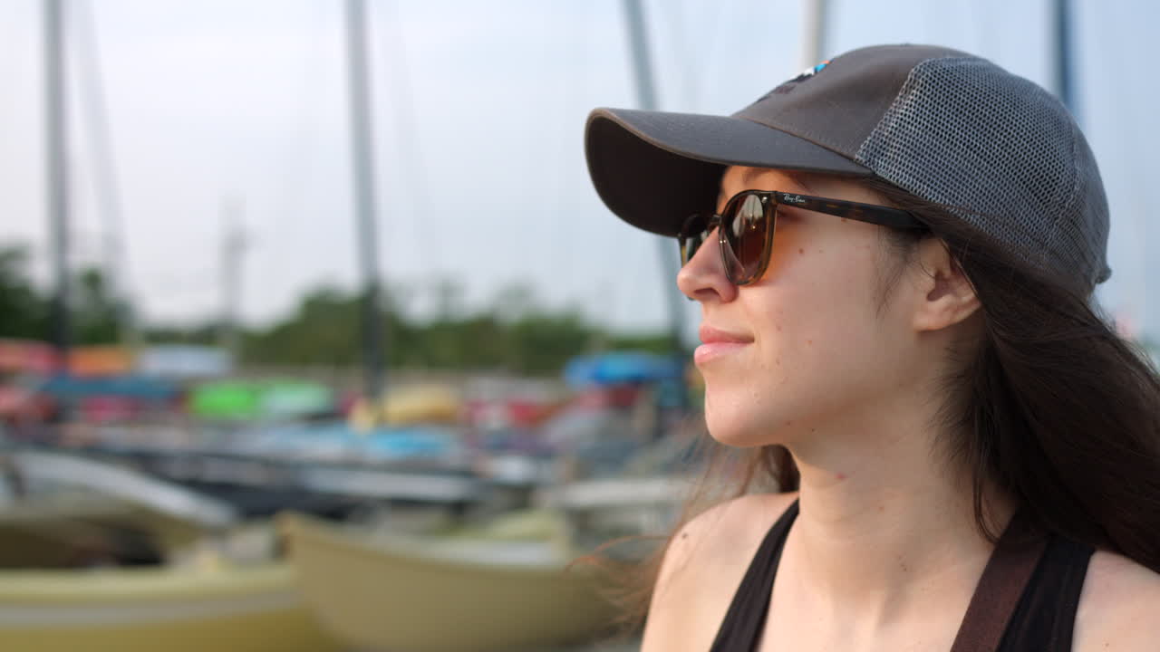 молодая девушка в кепке и солнцезащитных очках смотрит вдаль и наслаждается видом