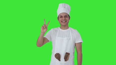 feliz chef profesional indio mostrando el signo de la victoria pantalla verde