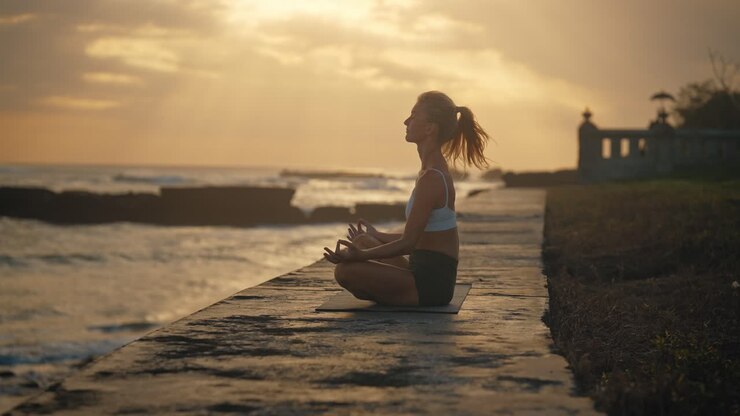 Donna sana seduta in posizione yoga di meditazione durante il tramonto a Bali.