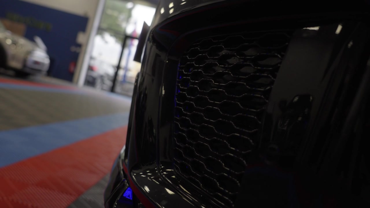 Griglia del radiatore a nido d'ape nera sul paraurti anteriore di un'auto sportiva di lusso, che evidenzia il suo design automobilistico premium, l'estetica tuning e l'intricato dettaglio della presa d'aria.