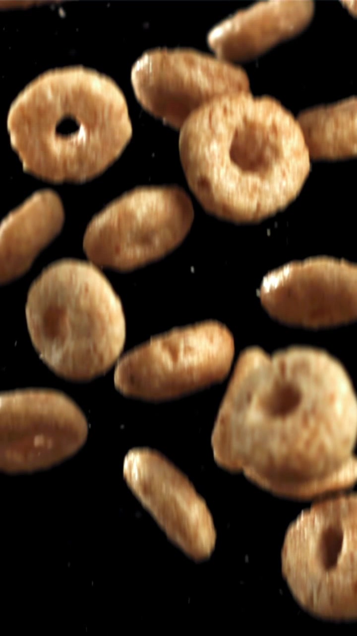 Anelli e ovali di cereali dorati che cadono al rallentatore