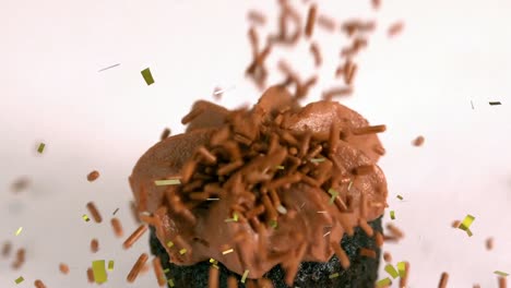 Animation-of-gold-confetti-falling-over-cupcake-with-chocolate-topping