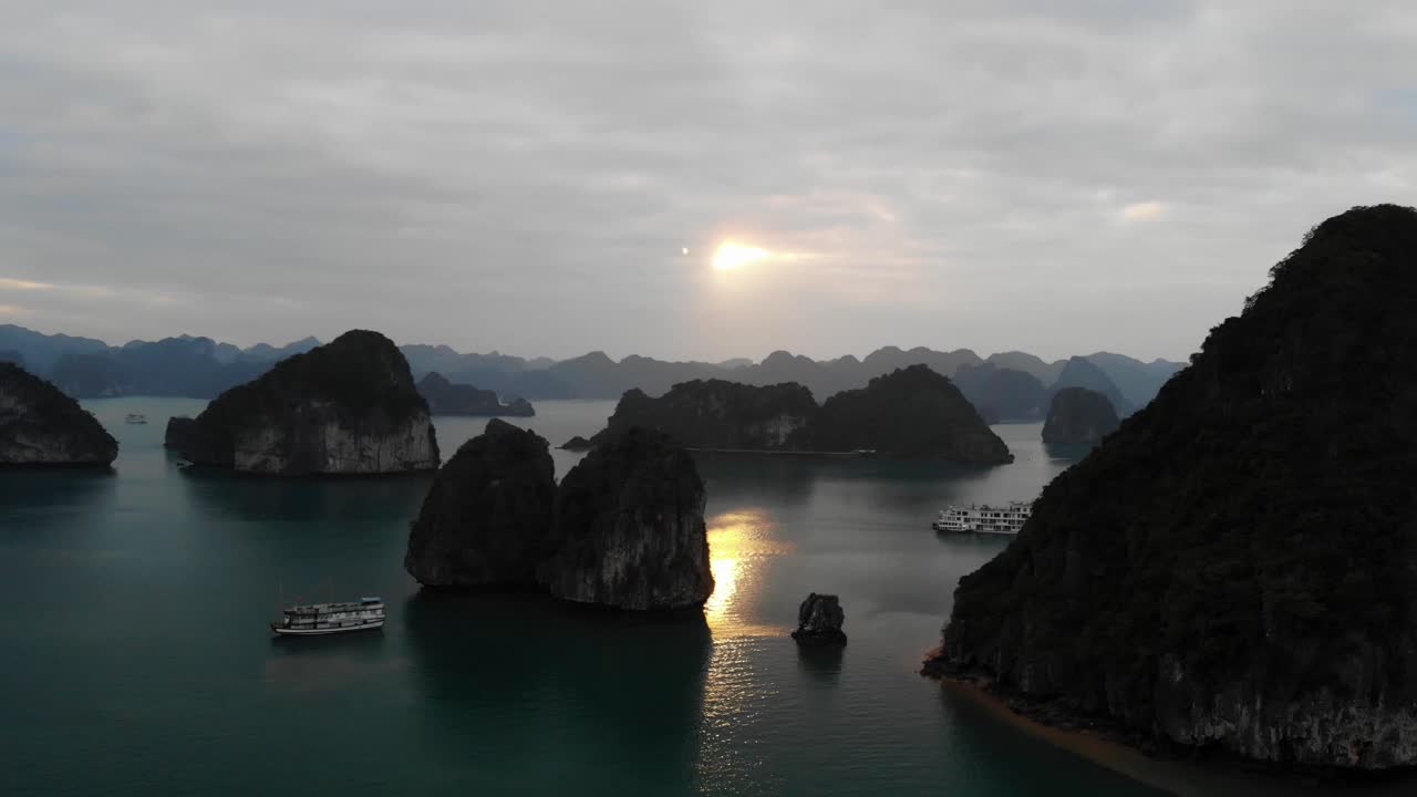 베트남 하롱베이의 공중 일몰, 탐험과 유람을 위한 크루즈 요트 보트가 있는 작은 바위섬 경치 좋은 군도