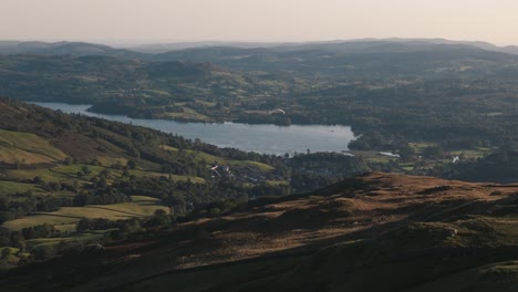 aerial tracking follows paraglider soaring over windermere lake in lake district, england on a beautiful sunset flight