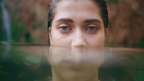 porträt von einem schwimmenden model, das eine türkisfarbene lagune posiert. brünette sucht nach einer kamera