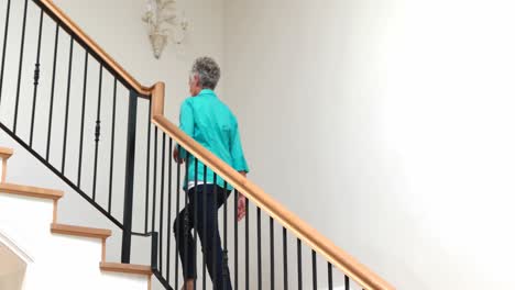 senior woman climbing upstairs with walking stick