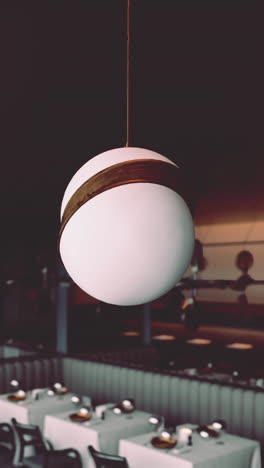 a modern restaurant interior with white round pendant lights over dining tables.