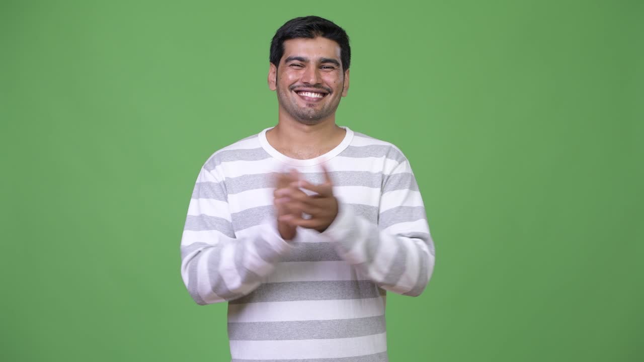 Young handsome Persian man clapping hands