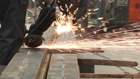 the grinder works at a metalwork factory and grinds metal parts with sparks