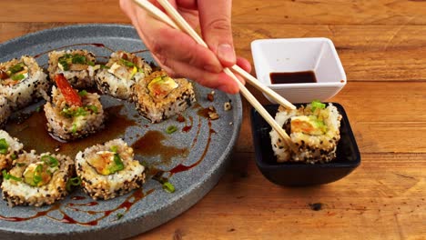 close-up of sushi plate being dipped in eel sauce