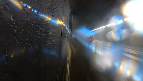 camera facing front of car with cars passing by in a tunnel with yellow and blue lights producing interesting texture and patterns