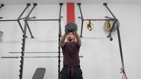 hombre levantando pesas rusas para karate en interiores con ambas manos en el gimnasio
