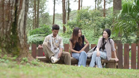 young asian indonesian friends sitting playing together on a wooden bench in forest park